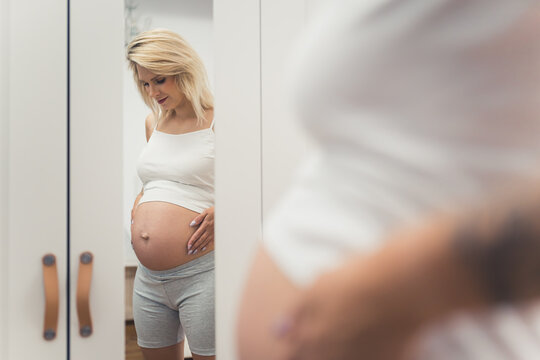 pregnant woman posing in front of the mirror, pregnancy concept. High quality photo