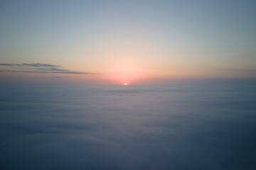 Aerial view from airplane window at high altitude of dense puffy cumulus clouds flying in evening