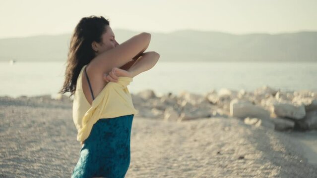 Slow motion video of a girl dropping her T-shirt and running to the sea to swim. Woman on vacation undresses and goes in a swimsuit to the ocean.