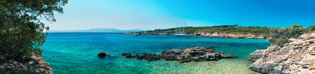 Amazing shot of a sea coast with clear blue water and stones in the foreground.
