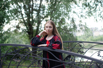 girl in national traditional ukrainian clothes. black and red embroidered dress. woman model posing in park outdoors