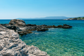 Amazing shot of a sea coast with clear blue water and stones in the foreground.