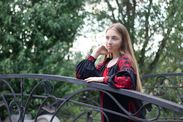 portrait of young woman wearing black and red vyshyvanka. national embroidered Ukrainian shirt. girl in dress outdoors in park. summer