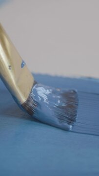 CLOSE UP, DOF: Painter uses a fine paintbrush to paint a blue line with oil paint. Unrecognizable artist drags their paintbrush across a blank slate of paper while creating their newest masterpiece.