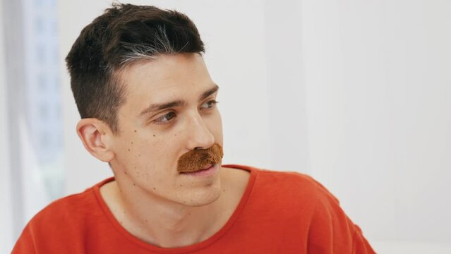 let's remember youth - portrait of a young Caucasian man with a fake mustache, white background. High quality 4k footage