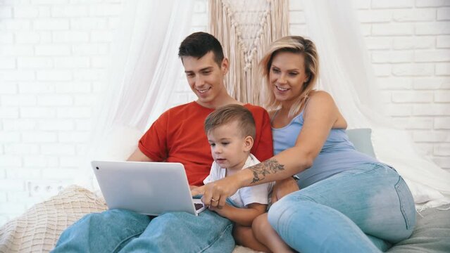 father, pregnant mother and little son watching something on the laptop. High quality 4k footage
