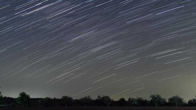 Time lapse of startrails at night with moving over silhouette of trees