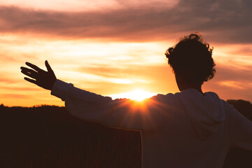 Silhouette of a man with arms raised and sunset in the background. Concept of happiness, mental...