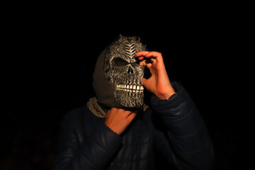 Defocus Halloween people. Person in grim reaper mask standing on black background. Dark night mood,...