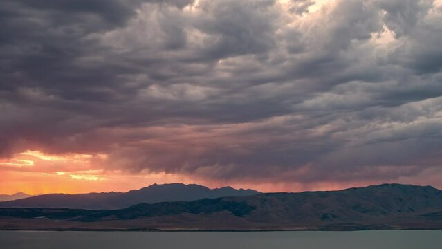 Timelapse of sunset glowing behind dark clouds as storm moves in.