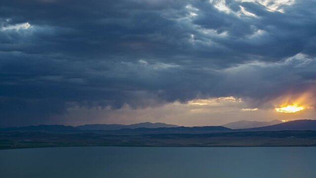 Timelapse of sunset and rainstorm moving in towards Utah Lake as dark clouds roll through the sky.