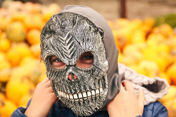 Defocus Halloween people portrait. Person in grim reaper mask standing on yellow pumpkin...