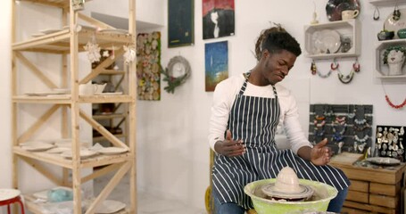 Young black man working on pottery wheel at workshop
