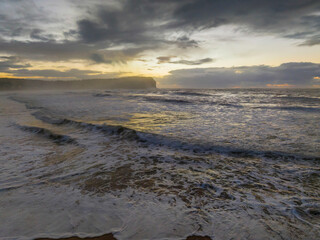 Fototapeta premium Sunrise at the seaside with large and powerful sets