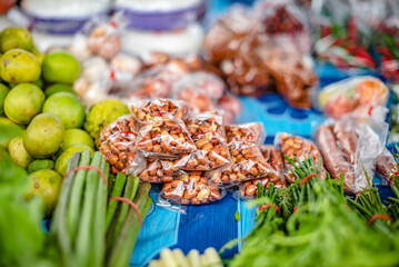 Roasted peanuts put in plastic bags are sold on vegetable pranks at a Thai roadside market.