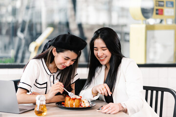 Asian woman enjoys eating a sweet dessert in a cafe with companion. Lifestyle and Cafe