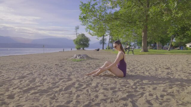 Side slow motion view of attractive girl sitting on a sandy beach