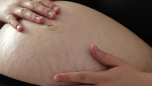 Close up of pregnant woman lying down, rubbing her belly. Third trimester