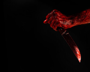 Man holding knife with bloody hand on black background. 