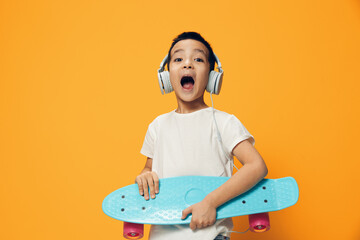 a cute little preschool-age boy is standing on an orange background in a white T-shirt holding his...