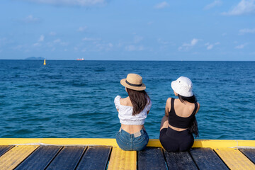 Two women friends or couple relaxing and watching views together on tropical beach travel summer holidays. Female tourists enjoy traveling to exotic nature in their leisure time. Friendship concept