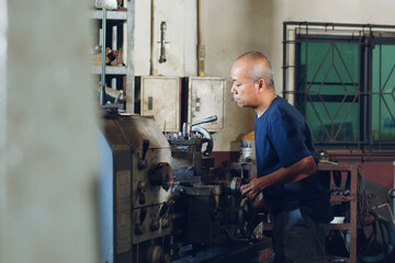 Technician asia worker using turning lathe machine for metalworking in workshop factory © Nattakorn