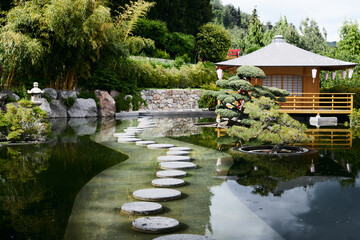 Japanese style house near the forest. A path of round stones across a pond in a Japanese garden....