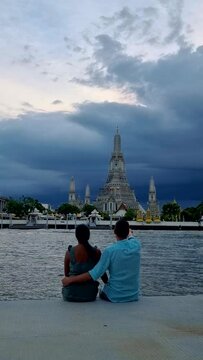 Wat Arun The Temple of Dawn Landmark of Bangkok, Thailand during the afternoon in Bangkok, couple men and woman at the waterfront in Bangkok during rainy monsoon season