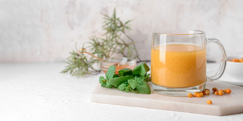 Cup of healthy sea buckthorn tea on light background with space for text