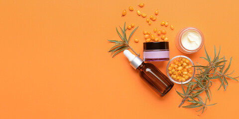 Healthy sea buckthorn cosmetics on orange background with space for text
