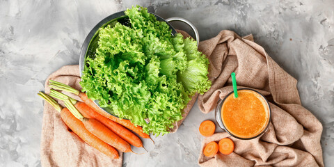 Composition with fresh carrot juice and lettuce salad on table