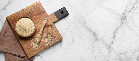 Bowl and scoops with sesame seeds on light background with space for text