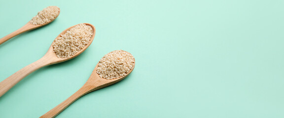 Wooden spoons with sesame seeds on color background with space for text