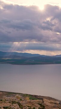 Storm clouds moving in the distance as light rays shine to the ground looking past Utah Lake.