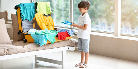Little boy packing suitcase at home. Travel concept