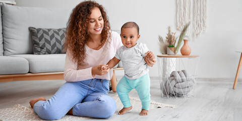 African-American woman teaching her little baby to walk at home