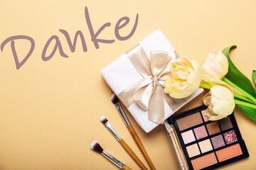 Gift box, eyeshadows, makeup brushes, tulips and word DANKE (German for Thanks) on beige background