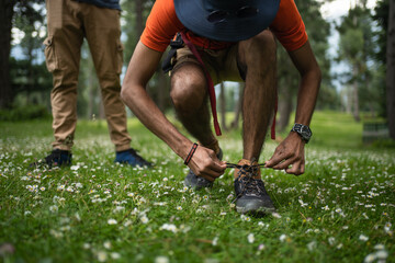 Man hiker with backpack stands on the Greenery and ties her shoe in Baisaran Valley, Pahalgam, Jaamu and Kashmir, India.