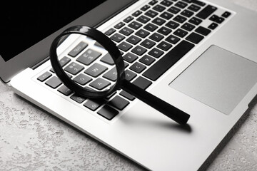 Laptop and magnifier on light background. Concept of search