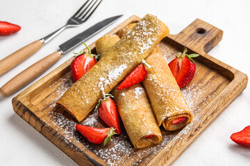 Board with thin pancakes, strawberries and sugar powder on white background, closeup