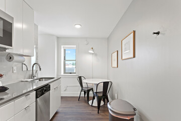 White apartment with wide open spaces, hardwood flooring and modern furniture. Used as a short term rental. 