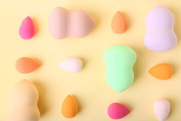 Many colorful makeup sponges on color background