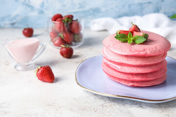 Plate with tasty pink pancakes and strawberry on table