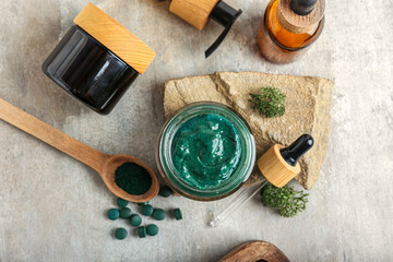 Composition with jar of spirulina facial mask and cosmetics on light background
