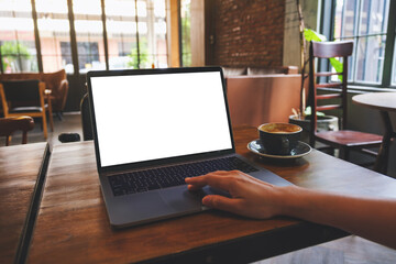 Mockup image of a woman using and touching on laptop computer touchpad with blank white desktop screen in cafe