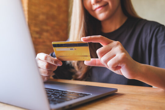 Closeup image of a woman holding credit cards while using laptop computer for online payment