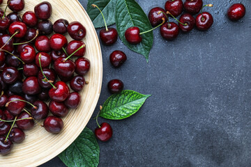 Plate with tasty cherries on dark background, closeup