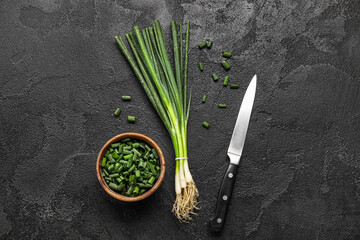 Composition with fresh green onion and knife on dark background