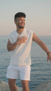 Happy young man smiling while enjoying dancing bachata outdoors near the sea. Viral video