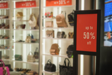 Discount percentage red sign display in fashion department store during sale season period. Sale tag of offering special promotion hanging in shopping mall, in department store background.